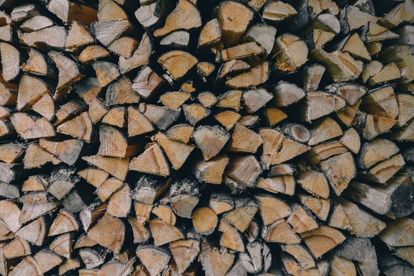 Stacked firewood showing split logs with exposed wood grain and charred bark